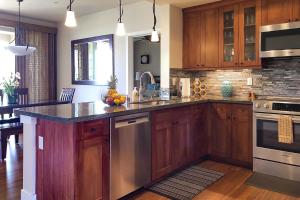 a kitchen with wooden cabinets and stainless steel appliances at Pili Mai 7H in Koloa