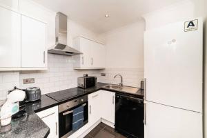 a kitchen with white cabinets and a black and white appliances at [Hyde Park - Oxford Street] London Duplex Apartment in London