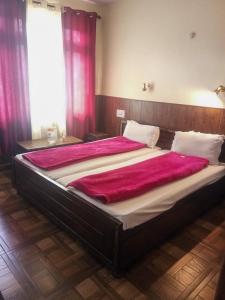 a large bed in a bedroom with pink curtains at Hotel Gyespa in Kyelang