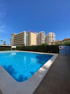 uma grande piscina azul com edifícios ao fundo em Apartamentos Cumbremar en Benicàssim em Benicàssim