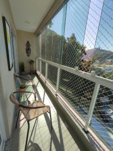 a balcony with two chairs and a view of the water at Apto Moderno Teresopolis in Teresópolis