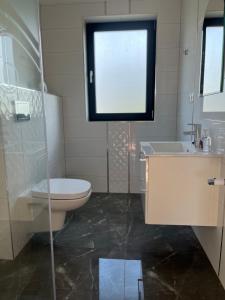 uma casa de banho com um WC, um lavatório e uma janela em Apartamenty Pod Jodłami em Sarbinowo