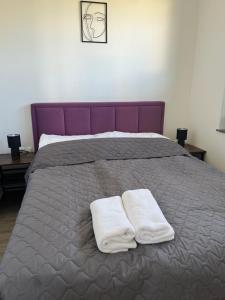uma cama roxa com duas toalhas brancas em Apartamenty Pod Jodłami em Sarbinowo
