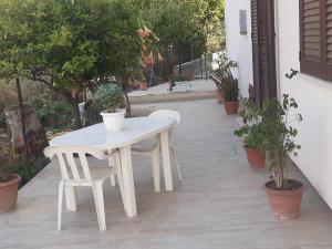 einen weißen Tisch und Stühle auf einer Terrasse mit Pflanzen in der Unterkunft Casa Consiglio in Realmonte