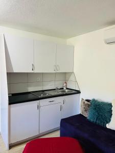 cocina con armarios blancos, fregadero y sofá en Apartment with river Una view / Ilma 1, en Bihać