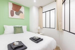 een slaapkamer met een wit bed met twee handdoeken erop bij Nets Inn - Botzaris in Parijs