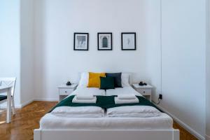 1 cama blanca en una habitación blanca con 3 cuadros en la pared en Budafoki Residence, en Budapest
