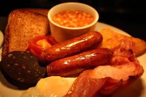 a plate of breakfast food with sausage eggs bacon and toast at The Belgrave Hotel Tenby in Tenby