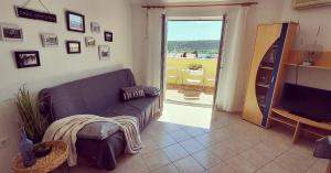 un soggiorno con un divano e una porta scorrevole in vetro di Sunshine Apartment a Stara Novalja