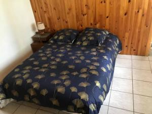 a bed with a blue comforter with gold leaves on it at Chalet rouge gorge in Mars
