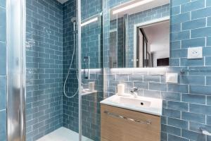 een blauwe betegelde badkamer met een wastafel en een douche bij Nets Inn - Botzaris in Parijs +74 foto's