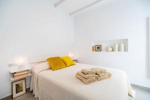 a white bedroom with a bed with yellow pillows and towels at Casa Bonita in Almería