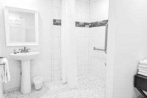 ein weißes Bad mit einem Waschbecken und einer Dusche in der Unterkunft Saltwater 102 1st Floor Low Tide ADA in Surf City