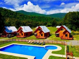 a group of cottages with a swimming pool in a field at Cabañas Agua Divina in Recinto