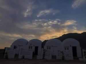 Nuweiba的住宿－Al Khalil Beach Camp，白色的建筑,背面有日落