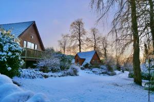 uma casa com neve no chão em frente dela em Ericht Holiday Lodges em Blairgowrie