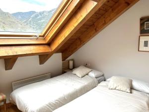 Duas camas num quarto com uma janela grande em Apartament amb llar de foc i altell a Llavorsí by RURAL D'ÀNEU em Llavorsí