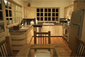a kitchen with wooden cabinets and a table and a refrigerator at Villa Turnage in Cabo San Lucas