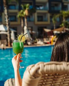 a woman holding up a green drink with a margarita at Waves Aqua Resort in Kenitra