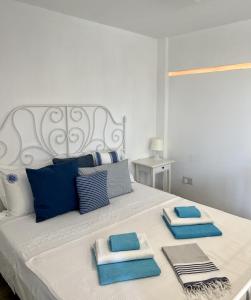 a white bed with blue and white pillows on it at The Dive Studio in Larnaka