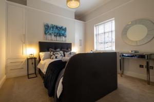 a bedroom with a large bed and a mirror at Stylish Central Apartment with Parking & Lift in Bury Saint Edmunds