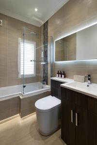 a bathroom with a toilet and a sink and a tub at Stylish Central Apartment with Parking & Lift in Bury Saint Edmunds