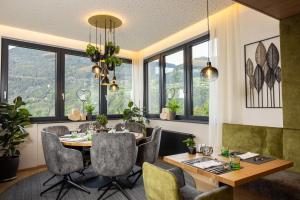 a dining room with a table and chairs and windows at Aktiv Panoramahotel Daniel in Sautens