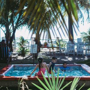 拉斯佩尼塔斯的住宿－Casita de Playa BOMALU，坐在游泳池里的男孩和女孩