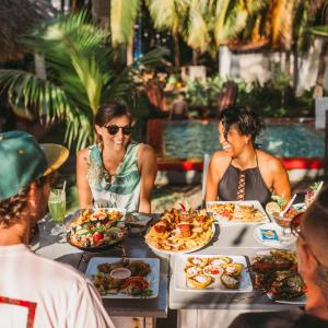 un grupo de personas sentadas alrededor de una mesa con comida en Casita de Playa BOMALU en Las Peñitas