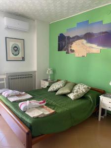 una camera da letto con un letto verde e asciugamani di Pousada Copacabana Praia - AFFITTACAMERE - Casa Vacanza a Porto Sant'Elpidio a Porto SantʼElpidio