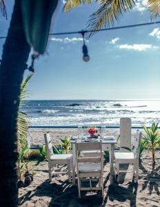 una mesa y sillas en la playa con el océano en Casita de Playa BOMALU, en Las Peñitas