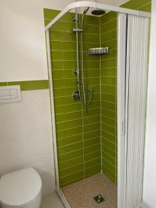 y baño con ducha de azulejos verdes y aseo. en Pousada Copacabana Praia - AFFITTACAMERE - Casa Vacanza a Porto Sant'Elpidio en Porto SantʼElpidio