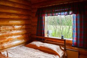 a bed in a log cabin with a window at Luha Talu 