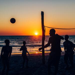Casita de Playa BOMALU في لاس بينيتاس: مجموعة من الناس يلعبون كرة الطائرة على الشاطئ عند غروب الشمس