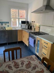 a kitchen with a stove and a sink and a table at Vine Cottage - Sandgate in Sandgate