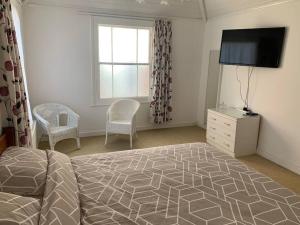 a bedroom with a bed and a flat screen tv at Vine Cottage - Sandgate in Sandgate