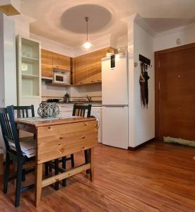 eine Küche mit einem Holztisch und einem weißen Kühlschrank in der Unterkunft Preciosa casa con jardín en Nueva de Llanes in Nueva de Llanes