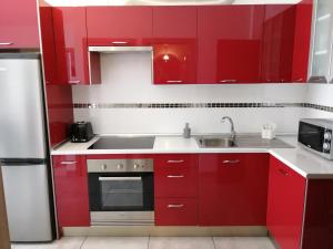 cocina roja con fregadero y nevera en Amplio apartamento 1 dormitorio - Playa Paraiso, en Playa Paraiso