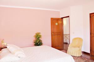 a white bedroom with a bed and a chair at Villa do Sol in Carcavelos