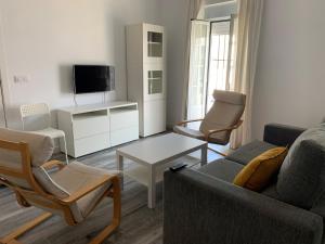 a living room with a couch and chairs and a tv at Apartamento Cañebolo in La Puebla de los Infantes