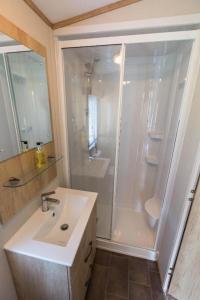 a white bathroom with a shower and a sink at Mallard Lake in South Cerney