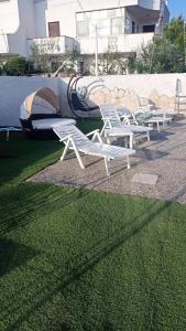 eine Reihe weißer Gartenstühle, die auf dem Gras sitzen in der Unterkunft I Girasoli in Bari