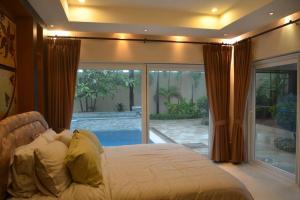 a bedroom with a bed and a sliding glass door at 4BRLuxury pool villa near Siam Country club (golf) in Ban Hui Yai Muk