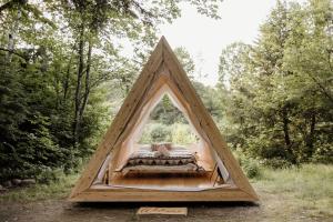 un lit dans une tente triangulaire angulaire angulaire dans une forêt dans l'établissement Lumen Nature Retreat, à Woodstock