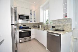 a kitchen with white cabinets and stainless steel appliances at Cupid's Way is a High-end New Home with Large PRIVATE Pool Snorkeling Cliff Jumping and Water Sports Equipment in Governorʼs Harbour