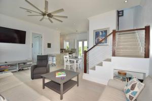 a living room with a ceiling fan and a staircase at Cupid's Way is a High-end New Home with Large PRIVATE Pool Snorkeling Cliff Jumping and Water Sports Equipment in Governorʼs Harbour