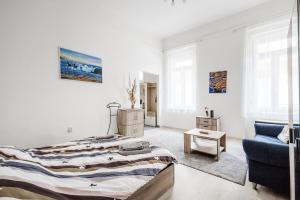 Un dormitorio blanco con una cama y una silla azul. en Lovely studio in the heart of Budapest, en Budapest