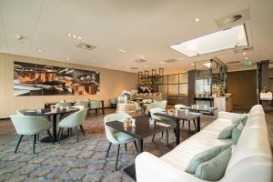 um restaurante com mesas e cadeiras e um sofá em Bilderberg Hotel De Keizerskroon em Apeldoorn