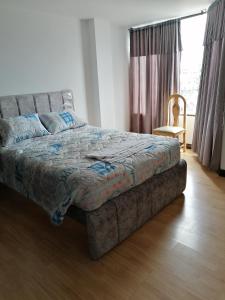 1 cama en un dormitorio con silla y ventana en Moderno apartamento para huespedes, en Ipiales