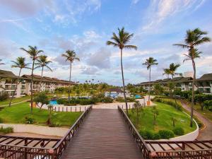 a boardwalk leading to a resort with palm trees at Beach Class Resort - Muro Alto Bangalô in Porto De Galinhas
